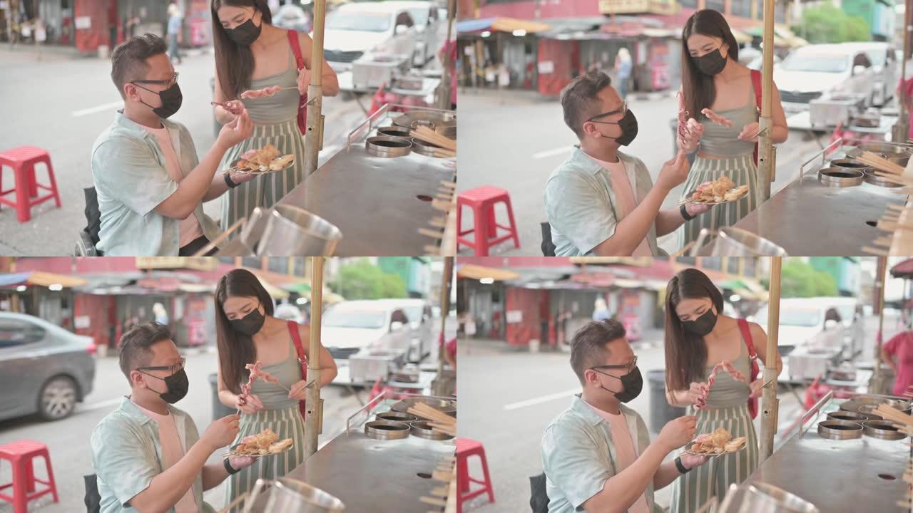 亚洲中国男性残疾人坐在轮椅上的女性朋友在八打灵街选择食物享受街头美食