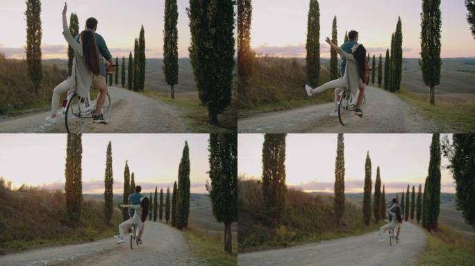 SLO MO夫妇在托斯卡纳的柏树林立的道路上骑着复古的自行车玩得开心