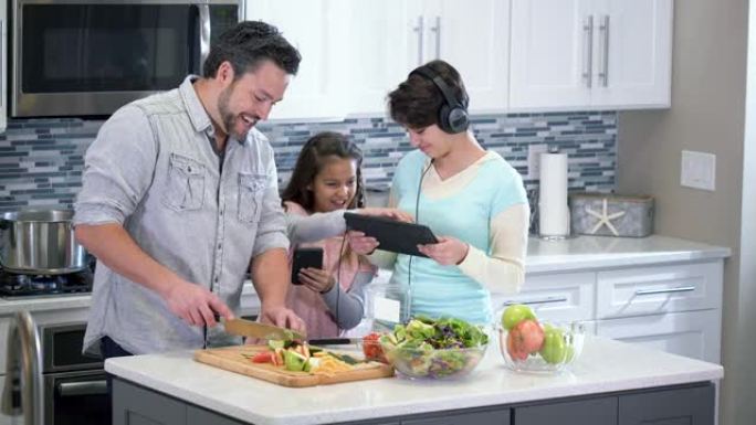 父亲在厨房里，孩子使用电子设备