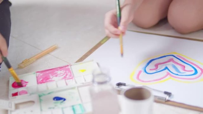 两个兄弟姐妹的亚洲女孩在家里的客厅里绘画和绘画她的艺术和手工艺。他们喜欢用水彩和画笔在白纸上创作艺术