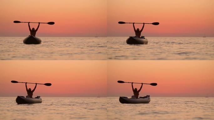 克罗地亚亚得里亚海日落时，在宁静的海洋上，无忧无虑的女人在船上拿着桨