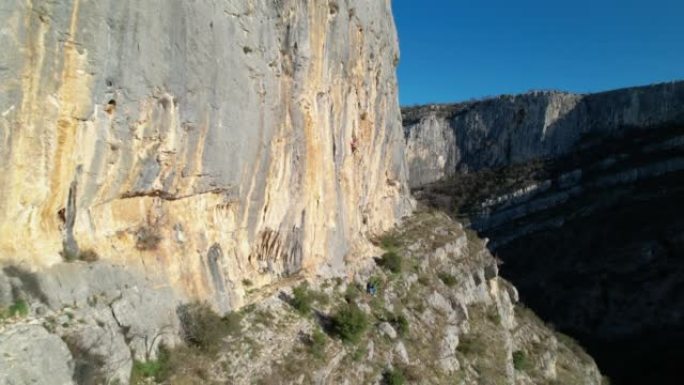 空中: 靠近阳光普照的攀岩墙飞行并接近女性攀岩者