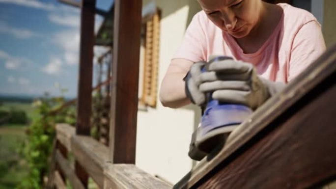 SLO MO女人使用电动工具抚平房屋上的木栅栏