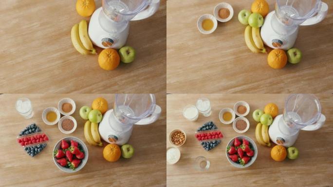 木制桌子上出现的新鲜农产品和其他健康奶昔成分的俯视图。水果，杏仁和配料以及用于制作冰沙的搅拌机。健康