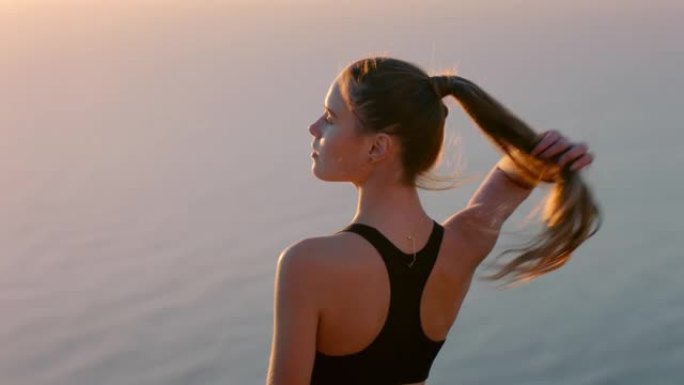 山顶上的女人在日落时看着美丽平静的海景站在悬崖边享受自由的女孩在思考登顶之旅
