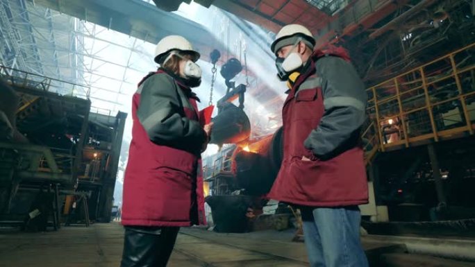 冶金厂与两名工业工人交谈。冶金工厂内部。