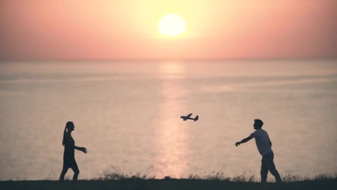 这对年轻夫妇将玩具飞机扔在海景背景上