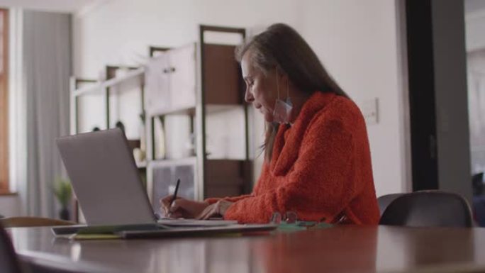 女人在家里的笔记本电脑上进行视频聊天时做笔记