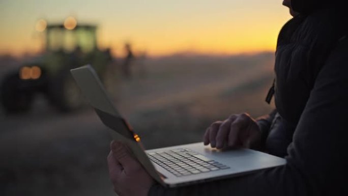 男性农民在日出时在农田使用笔记本电脑