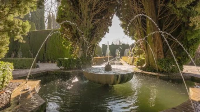 阿尔罕布拉的马罗尼菲花园的喷泉被树木包围。格拉纳达,西班牙。镜头在树木之间移动，来到马罗里菲花园中有