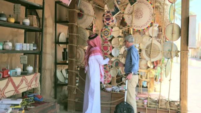 游客与沙特商人交谈并看着商品