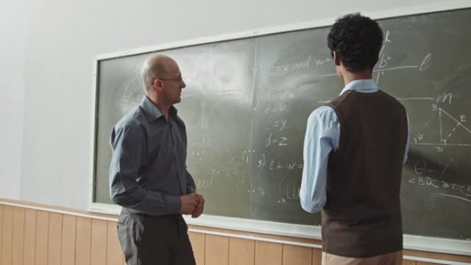 学生和教授在黑板上解决几何问题