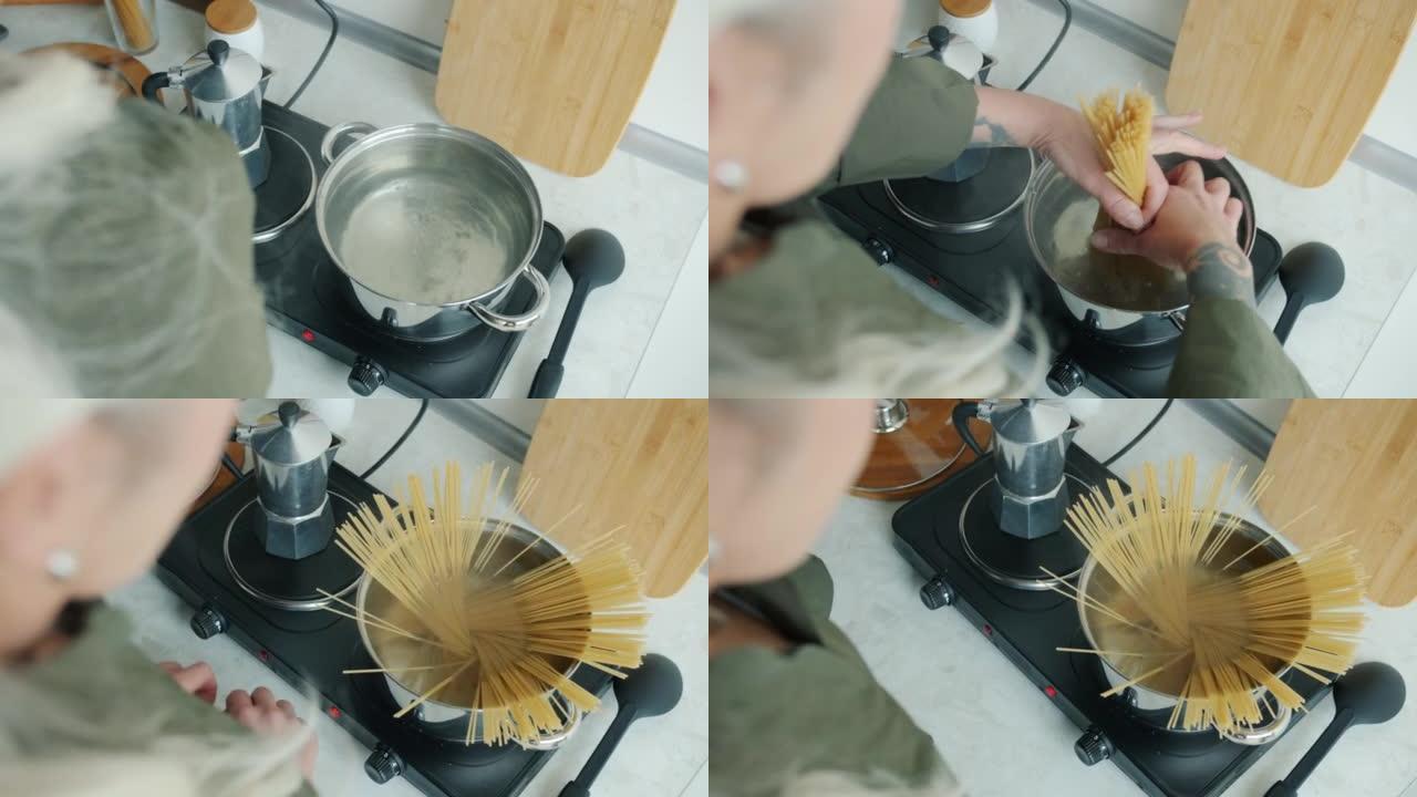 女性手把意大利面放在锅里在家厨房做饭的特写