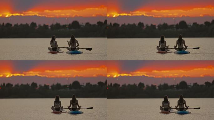 两名年轻女子在皮划艇上莲花姿势冥想瑜伽的后视图