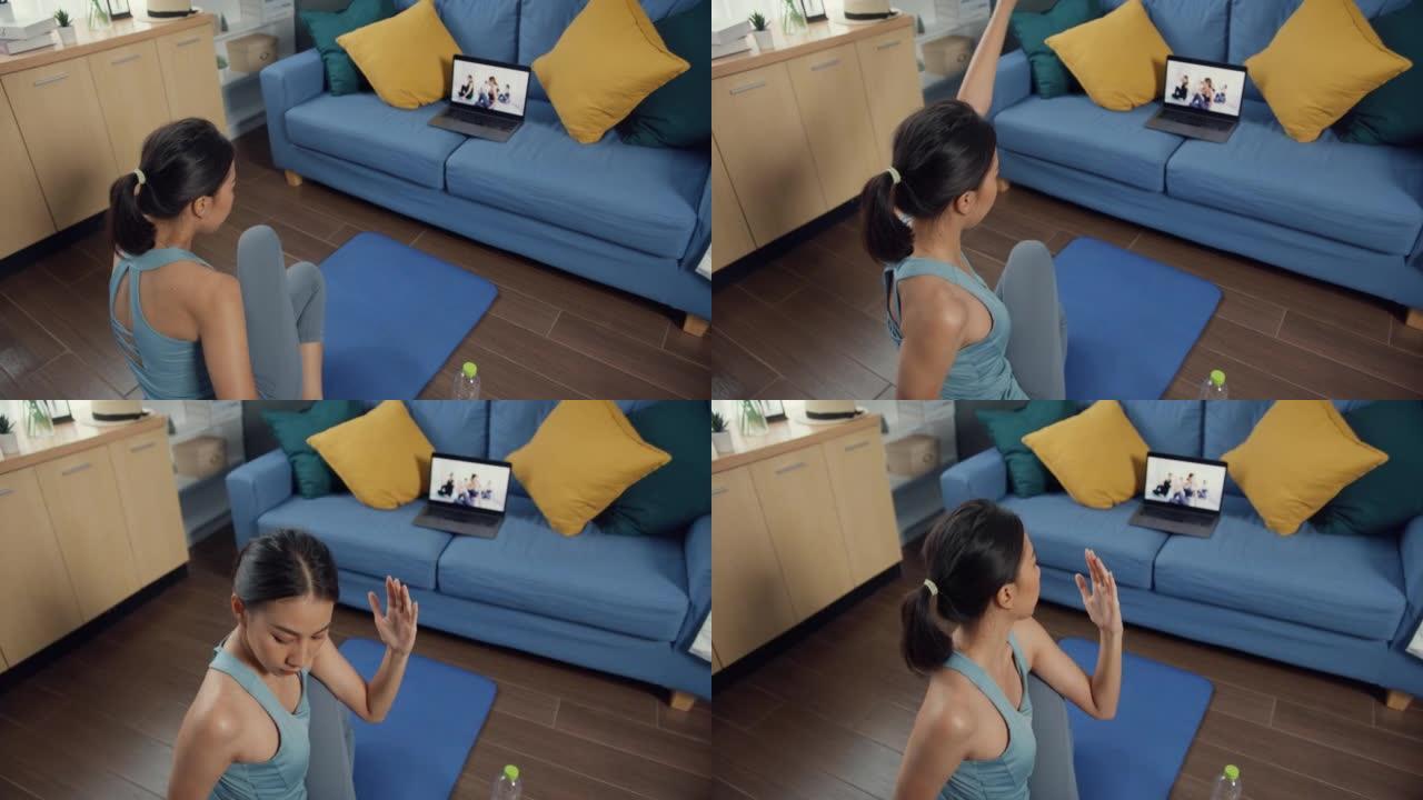 年轻迷人的亚洲女性在运动服网站在地板上的垫子上虚拟健身课与一群人在笔记本电脑的视频会议上练习瑜伽在家