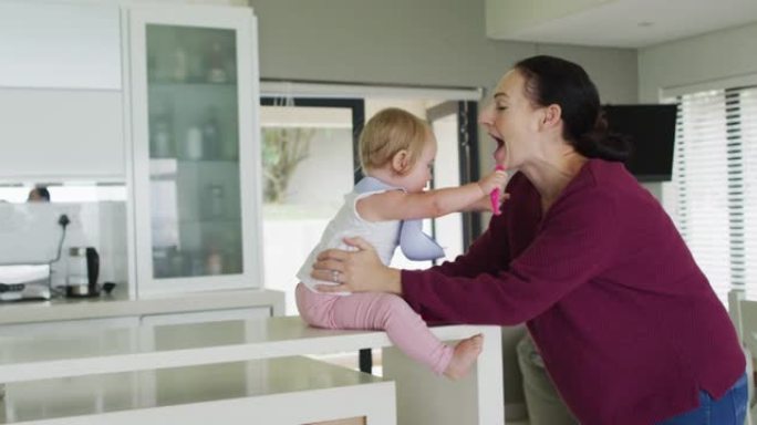 白人母亲在家里的厨房里和婴儿玩耍时接吻