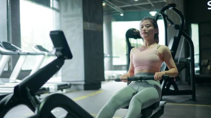 年轻女子在健身房用划船机锻炼