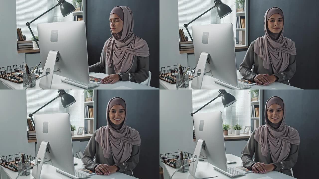 穆斯林妇女使用计算机并在相机上微笑