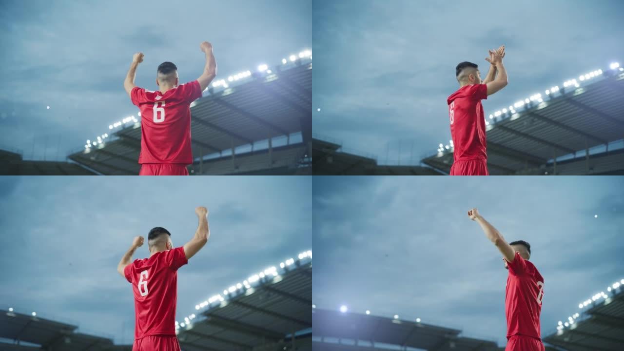 足球比赛冠军: 英俊的红队足球运动员的肖像站着，摆姿势，微笑，举手欢呼。职业足球运动员，庆祝赢得杯赛