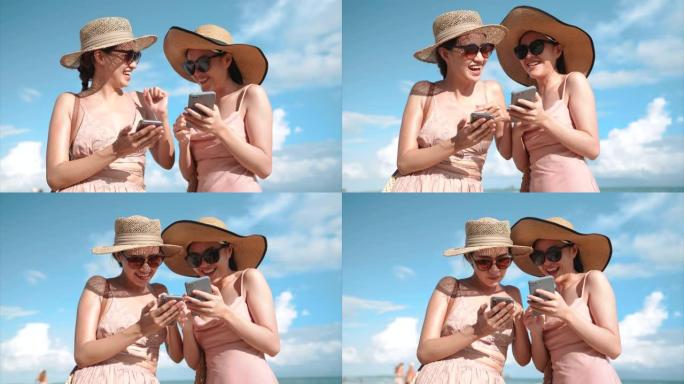 两名亚洲妇女喜欢在海滩上一起使用智能手机