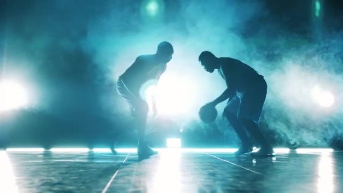 男球员正试图从他的对手那里夺走篮球。黑暗中的篮球运动员。