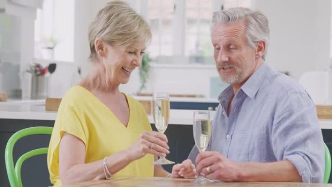 亲吻退休夫妇在约会之夜一起在家用一杯香槟庆祝