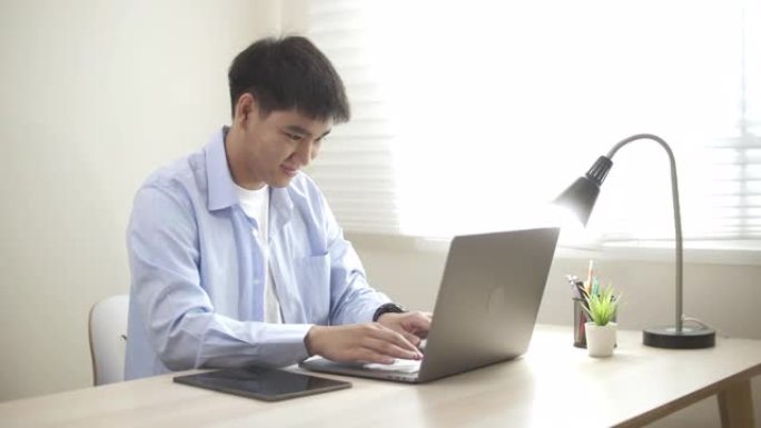 亚洲男子在家中使用笔记本电脑