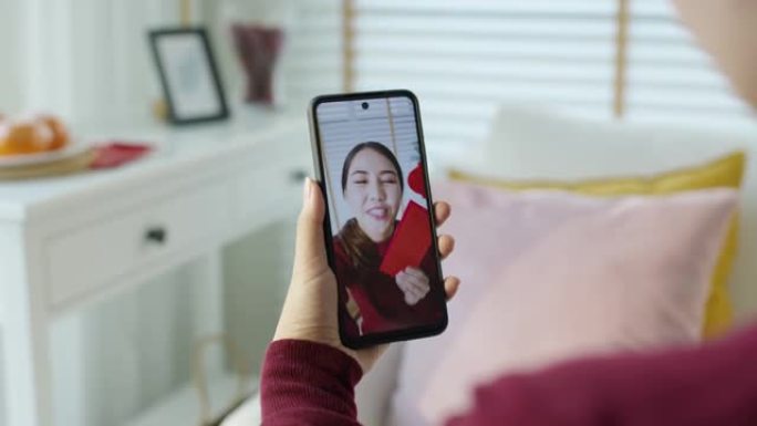 视角自拍视频镜头迷人美丽的年轻亚洲女士穿着红色春节庆祝服装快乐微笑交谈，期待相机手机祝愿农历节日。