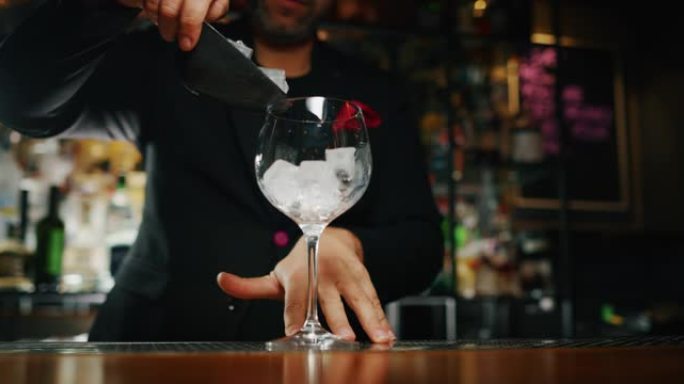 专业调酒师正在将专业的水晶持久冰块放入酒吧或迪斯科俱乐部，与顾客一起准备酒精鸡尾酒。