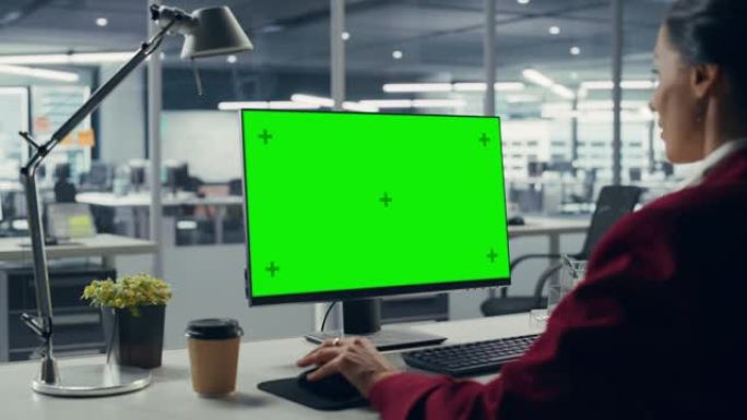 成功的白人女商人坐在办公桌前，在办公室里用绿屏笔记本电脑工作。美丽的商人使用色度键显示。肩以上静态射
