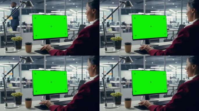 成功的白人女商人坐在办公桌前，在办公室里用绿屏笔记本电脑工作。美丽的商人使用色度键显示。肩以上静态射