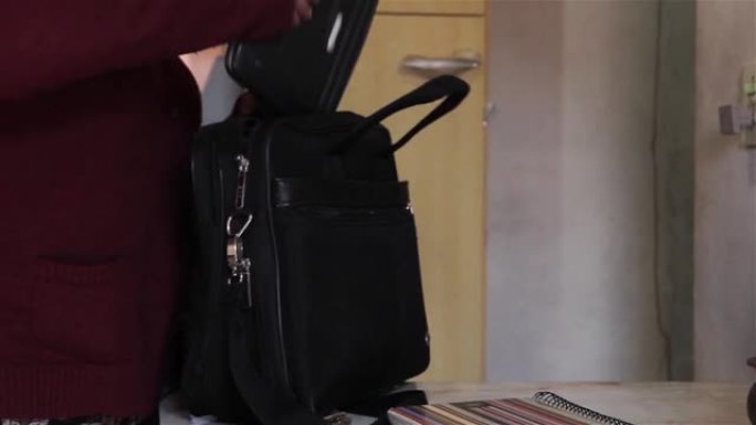 一个女人准备离开家，把所有东西都装在手提包里。特写。