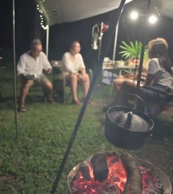 亚洲华人家庭露营晚餐，篝火上方的大锅烧火柴火烧火