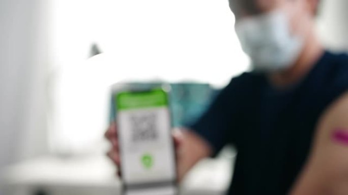 新型冠状病毒肺炎大流行期间，在海关的手机上戴口罩的亚洲男子展示数字疫苗护照应用程序