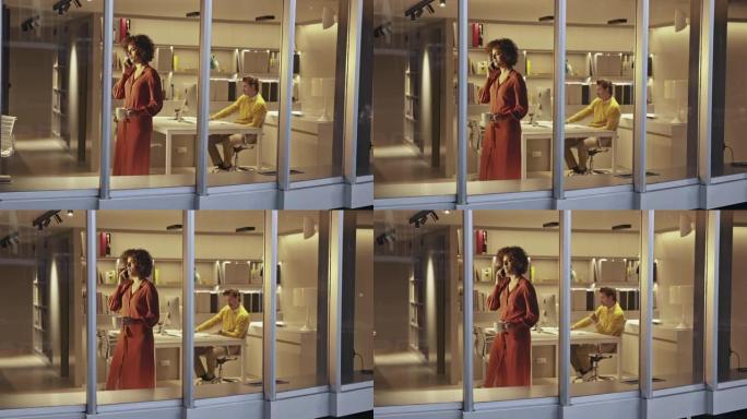 深夜在现代办公室使用手机的女性设计师通过窗户观看外部视频
