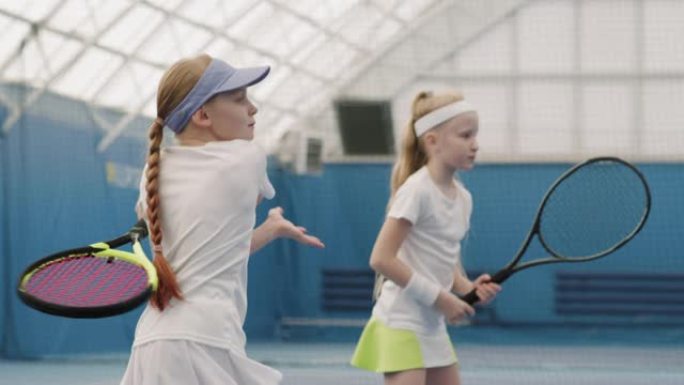 年轻女孩在球场上练习网球