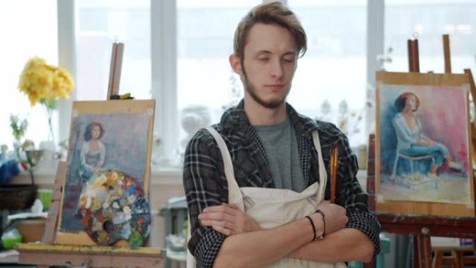 站在画室里拿着画笔的富有创造力的年轻人艺术家的肖像