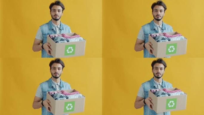 年轻混血儿拿着一盒旧衣服回收的慢动作肖像