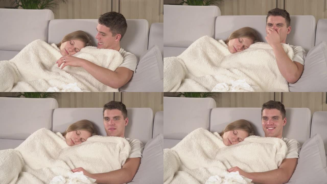 特写: 年轻夫妇在毯子下休息，一边看电视，一边感染流感