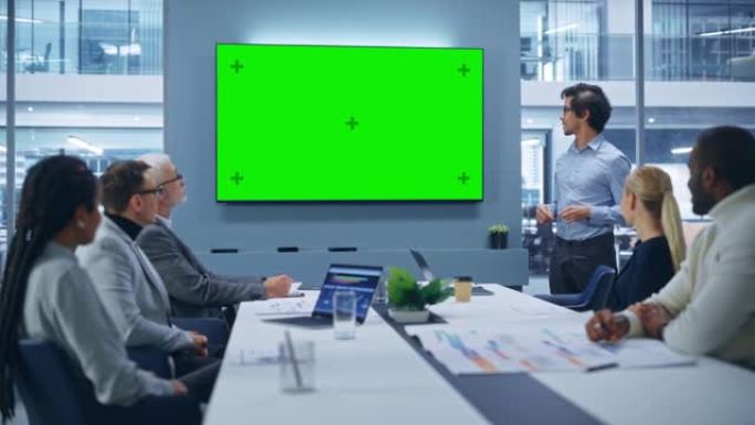 办公室会议室会议演示: 魅力拉丁商人谈话，使用绿屏色度键墙电视。成功向多民族投资者群体展示电子商务产