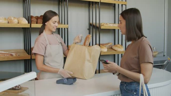 面包店女员工向顾客出售食品