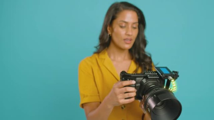 摄影棚中女性摄像师周围的运动图形，摄影机在蓝色背景上拍摄视频