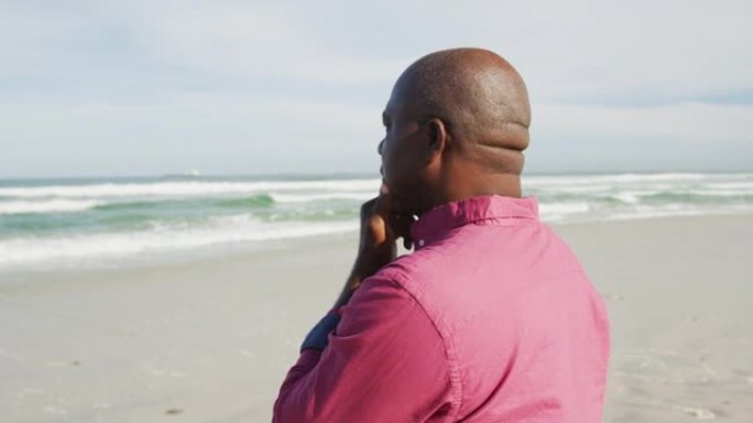 非裔美国男子在沙滩上漫步，看着大海