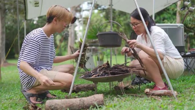 亚洲中国十几岁的男孩和他的母亲在帐篷旁准备煮汤准备做饭