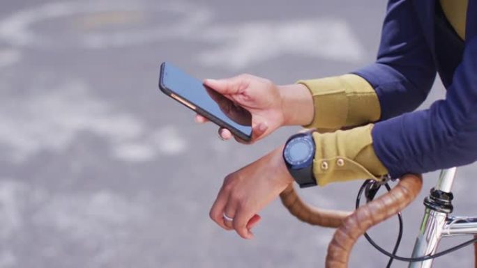 非裔美国妇女在骑自行车的街道上使用智能手机