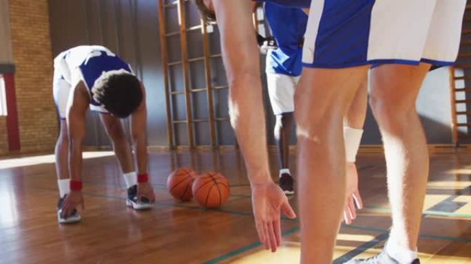 多样化的男子篮球队穿着蓝色运动服并伸展运动