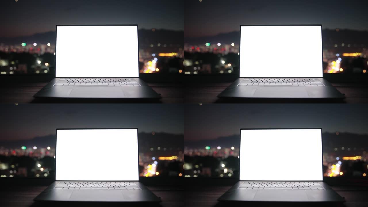 城市夜晚背景的白屏笔记本电脑