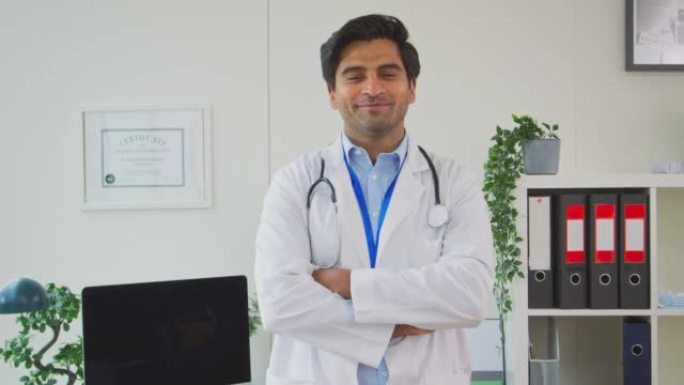 微笑的男性医生或全科医生的肖像，听诊器穿着白色外套站在办公室-慢动作拍摄