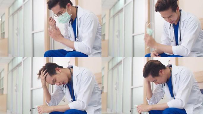 年轻的亚洲医生劳累严重，男性成熟的医护人员坐下来很劳累
