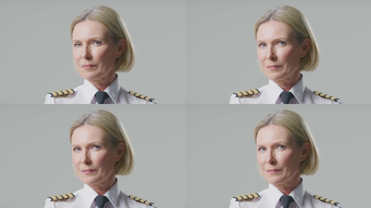 在朴素的背景下，严肃的成熟女性航空公司飞行员或船长的工作室肖像